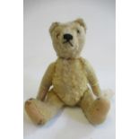 A pre-war Steiff jointed teddy, straw filled, sewn nose, amber eyes, felt pads and silvered button