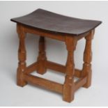 A ROBERT THOMPSON ADZED OAK STOOL of dished oblong form with faceted baluster turned and block