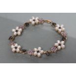 A CULTURED PEARL AND GEM BRACELET, each six petalled daisy head centred by a black diamond and