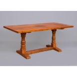 A ROBERT THOMPSON ADZED OAK DINING TABLE, the rounded oblong plank top on trestle base with