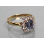 A SAPPHIRE AND DIAMOND CLUSTER RING, the square cut Celanese sapphire claw set to a border of