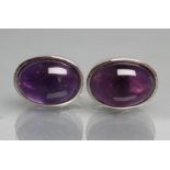 A PAIR OF AMETHYST CUFFLINKS, the plain oval cabochon polished stones collet set in silver with