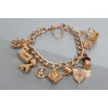 A CURB LINK CHAIN BRACELET, each link stamped 9.375 with dog clip fastener and ten charms, 56g gross