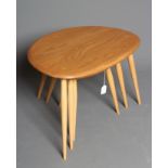 AN ERCOL BEECH AND ELM NEST OF THREE "PEBBLE" TABLES, the well figured tops raised on turned