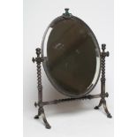 AN ARTS AND CRAFTS SILVERED STEEL FRAMED TOILET MIRROR, the oval bevelled plate in a plain frame
