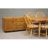 AN ERCOL WINDSOR BEECH AND ELM DINING SUITE comprising an extending table with rounded oblong top