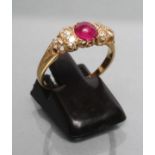 A RUBY AND DIAMOND RING, the circular cabochon polished ruby with three old mixed cut diamonds to