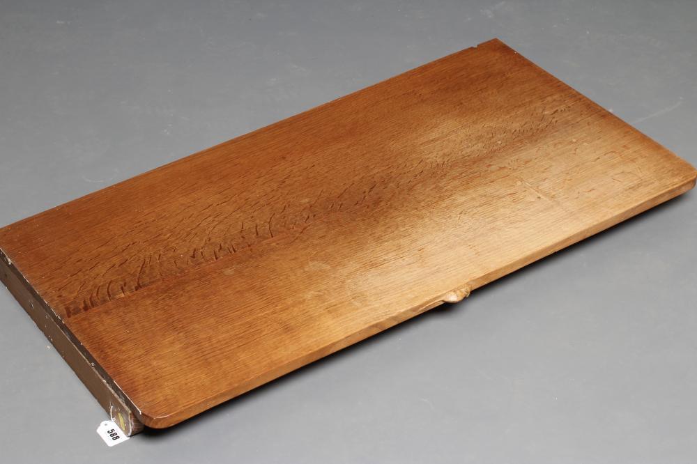 A ROBERT THOMPSON OAK WALL SHELF of rounded oblong form with carved mouse trademark in high