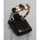 A SAPPHIRE AND DIAMOND RING, the three oval facet cut sapphires claw set with two pairs of round