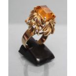 A COCKTAIL RING, the square cut citrine claw set to a high open knot border on a plain wide shank,