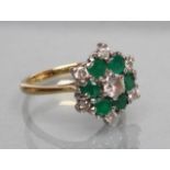 A DIAMOND AND EMERALD CLUSTER RING, the central diamond of approximately 0.20cts claw set to a