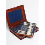 A SET OF TWELVE PAIRS OF VICTORIAN EPNS DESSERT KNIVES AND FORKS with scroll engraved blades and