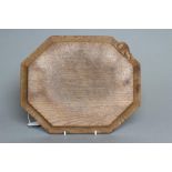 ROBERT THOMPSON, an oak chopping board of canted oblong form, the concave moulded edge with carved