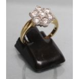 A SEVEN STONE DIAMOND CLUSTER RING, the point set stones on plain shoulders and gold shank, size
