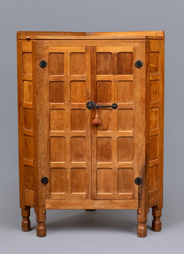 A ROBERT THOMPSON ADZED OAK CORNER CUPBOARD, the moulded edged top with ledge back, two multi