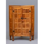 A ROBERT THOMPSON ADZED OAK CORNER CUPBOARD, the moulded edged top with ledge back, two multi