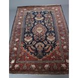 A PERSIAN PRAYER RUG, the navy blue mirhab with lantern and central red floral gul featuring a