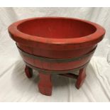 Large red painted Chinese wooden bowl, brass ring bound raised on four feet. 36 h x 53cms w.