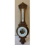 An oak cased aneroid barometer with carved body, 87cms h. Condition ReportGood condition apart