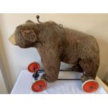 A mid 20thC straw filled growler bear on wheels, possibly Steiff. 70cms l x 55cms h. Condition