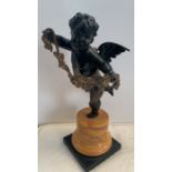 Bronze winged putto standing on one leg holding garland of flowers, slate base with Sienna marble