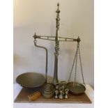 Set of brass balance scales and weights on mahogany base including 5 bell weights. Condition