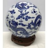 Large Chinese Blue and White Dragon patterned pottery ball on carved wooden stand base 35cms h.