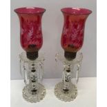 A pair of glass candlesticks with cranberry coloured shades engraved with a leaf decoration. 13cm