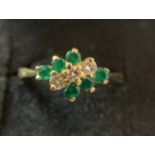 An 18ct emerald and diamond ring, size M. Size emeralds and three diamonds. 3.2gms.Condition