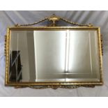 Large decorative gilt framed bevel edged wall mirror with decorative bow frame. Mirror size 87cm x