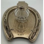 A hallmarked silver inkwell and stand in the form of a horseshoe with silver lidded glass inkwell.