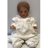 A large German pot headed doll with composite body, open/close eyes and stamped to the back of the