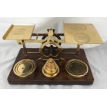 A set of S Mordan & Co brass postal scales on a wooden base with a set of brass weights to weigh