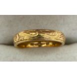 A 22ct gold wedding band with decorative etching to surface. Size K, 4.8gms.