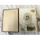 A leather bound early 20thC photo album with bordered pages containing photographs of family