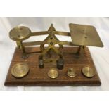 Brass postal scales on a wooden base with weights , half, one and two ounces. Base 18cms w x 10cms x