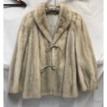 A ladies mid length mink jacket with embroidered silk lining and leather ties fastening to front.