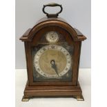 A mahogany cased Elliot mantle clock with a cherub decorated brass face. Retailed by Carmichaels