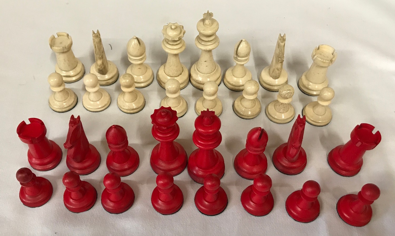 A carved bone red and white chess set. Complete.Condition ReportOne red pawn with glued tip. Overall