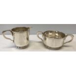 A hallmarked cream jug and sugar bowl by R&C London 1933. Cream jug 7cms h, sugar 5cms h. Total