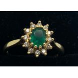 An 18ct gold ring set with single emerald surrounded by diamonds, size L. 3.2gms total weight.