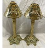 A pair of brass candlesticks with Corinthian columns and decorative pierced shades and base. Approx.