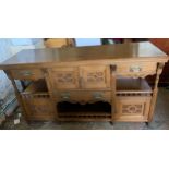 An early 20thC oak Arts and Crafts sideboard. Three cupboards and three drawers with brass handles