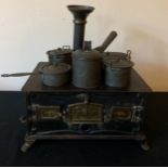 A vintage child's tinplate stove and pans. 24 x 16cms.Condition ReportGood condition.