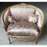 A 19thc carved gilded wooden framed single seat sofa with floral upholstery and a pair of tassel