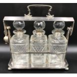 A silver plated framed tantalus containing 3 square decanters with sterling silver stopper bases.