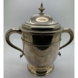 A silver lidded twin handled cup with faint inscription to front. London 1911, maker Johnson