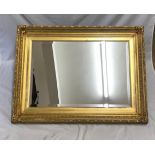 Large decorative gilt framed bevel edged wall mirror. Mirror size 70cm x 47cm. Frame size 91cm x