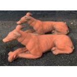 Two vintage terracotta coloured garden ornaments in the form of recumbent dogs. 68cms l.Condition