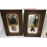 A pair of carved oak framed bevelled wall mirrors painted with floral decoration and engraved